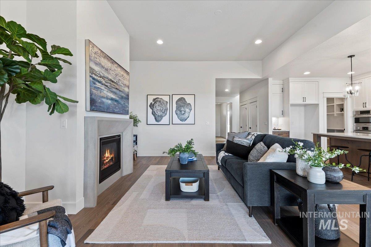 Living area featuring wood finished floors, recessed lighting, a glass covered fireplace, and a chandelier
