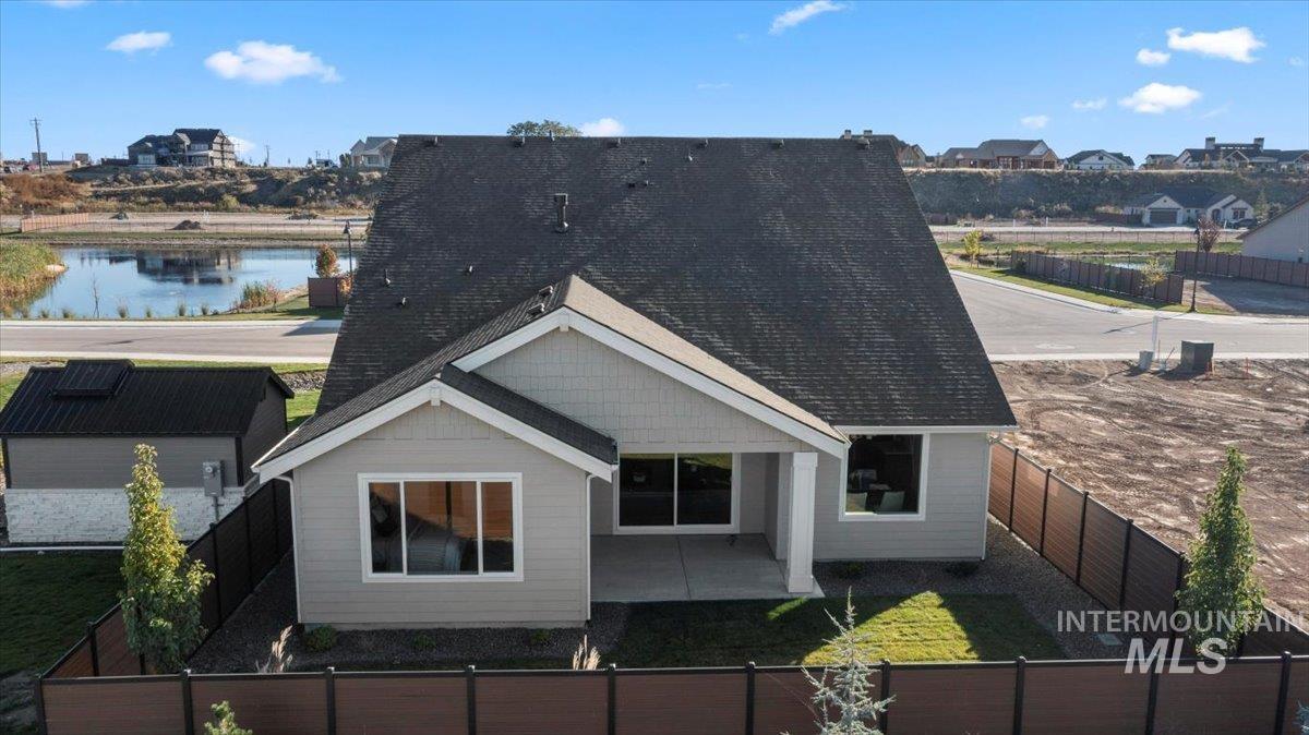 Back of house featuring a fenced backyard, roof with shingles, and a patio area
