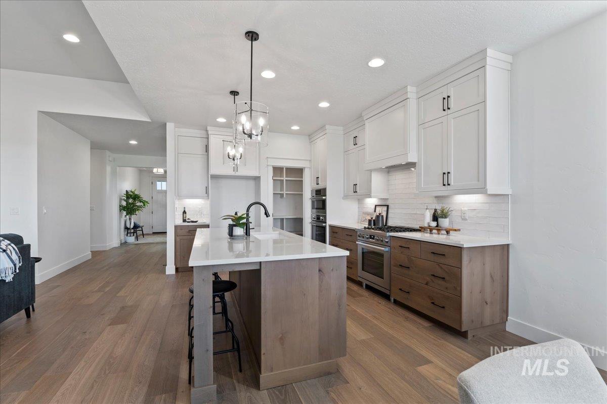 Kitchen with white cabinetry, a kitchen bar, tasteful backsplash, an island with sink, and brown cabinets