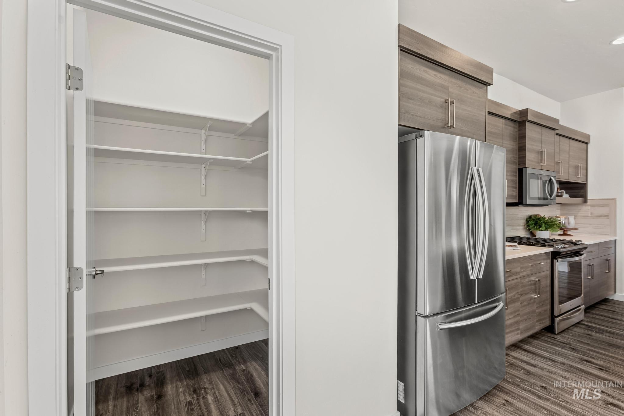 Kitchen featuring stainless steel appliances, modern cabinets, dark wood finished floors, and decorative backsplash
