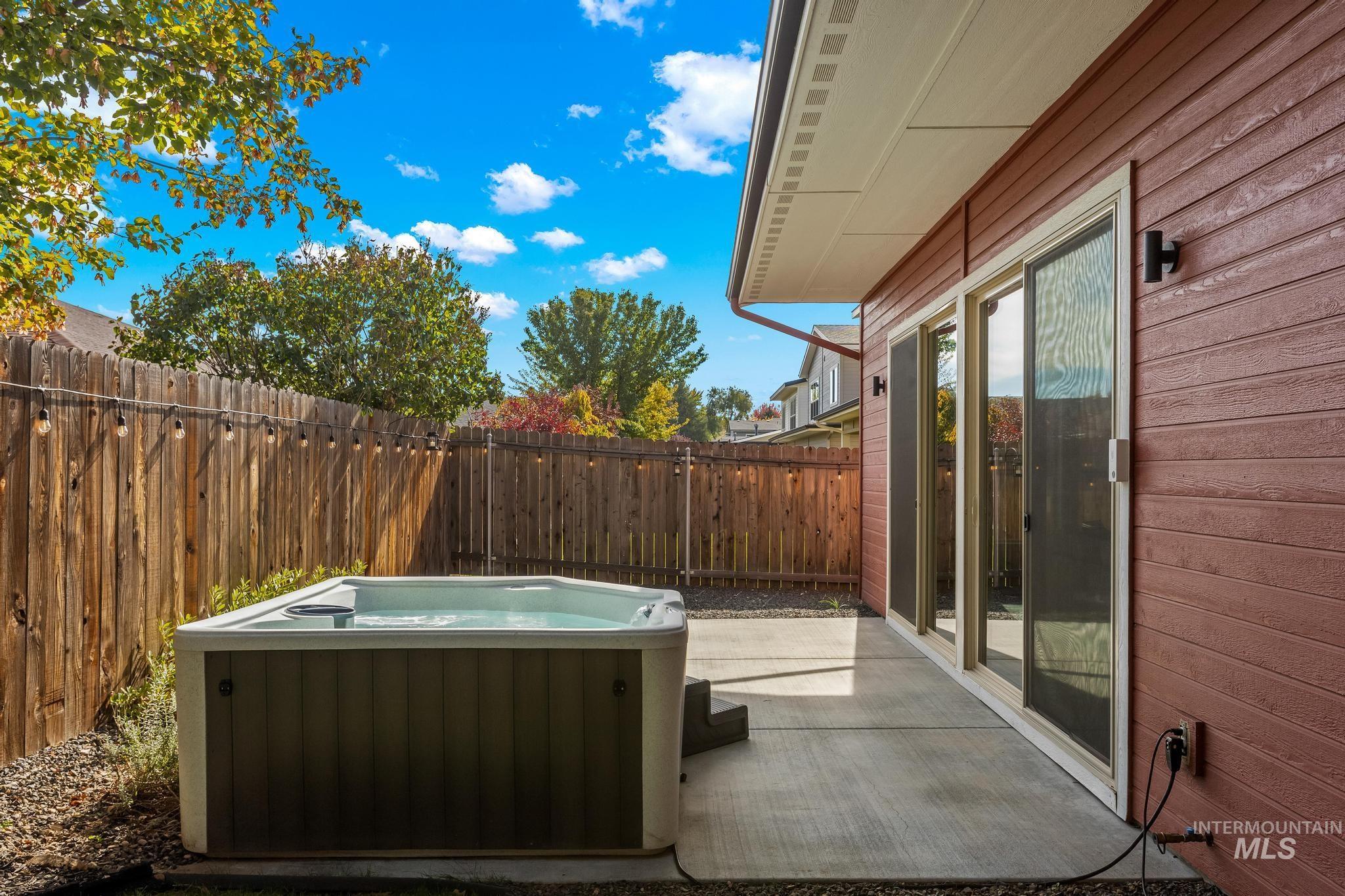 Fenced backyard featuring a patio and a hot tub