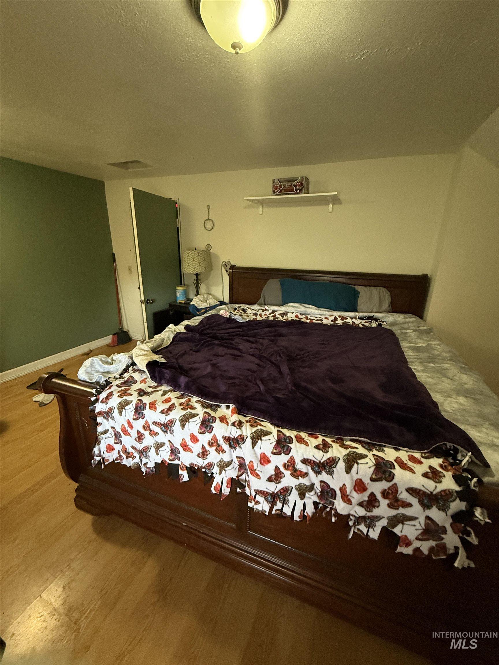 Bedroom with a textured ceiling and wood finished floors