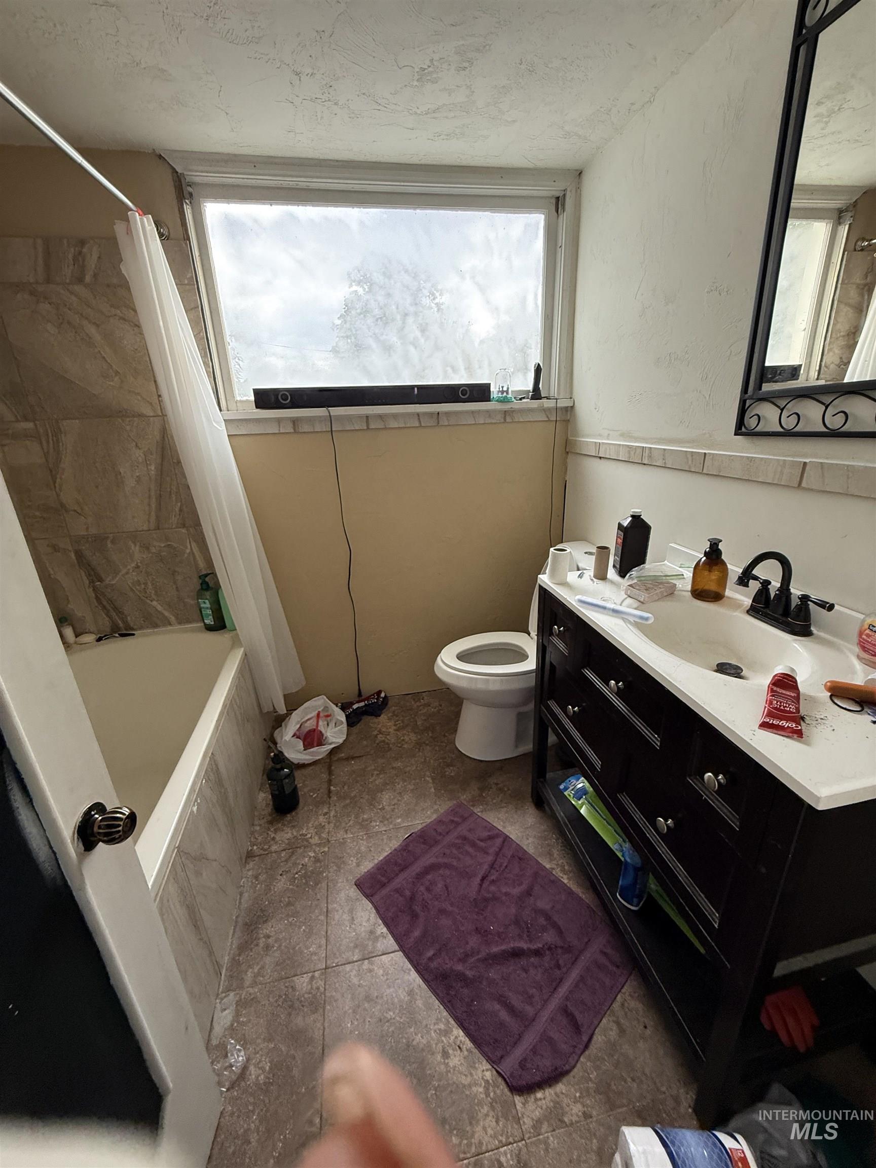 Bathroom featuring tiled shower / bath, vanity, tile patterned flooring, and a textured ceiling
