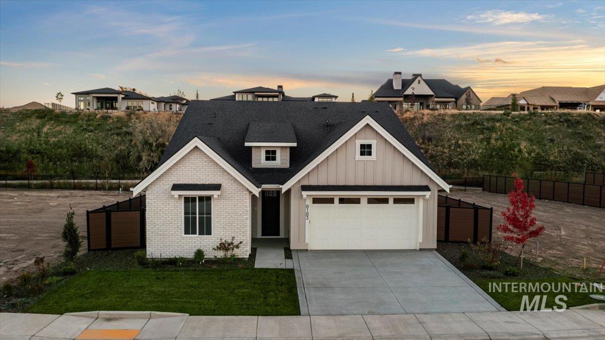 View of front of home with board and batten siding, concrete driveway, a garage, brick siding, and a shingled roof