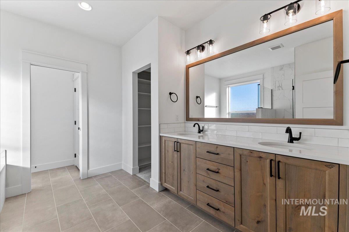 Bathroom featuring double vanity, light tile patterned flooring, recessed lighting, and a spacious closet