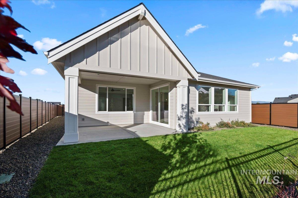 Back of house featuring board and batten siding, a patio, a fenced backyard, and a ceiling fan