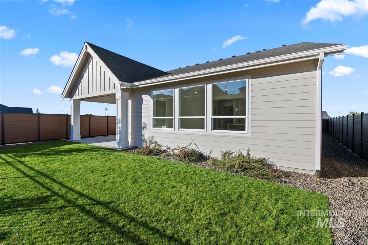 View of side of property with a fenced backyard, a patio area, roof with shingles, and board and batten siding