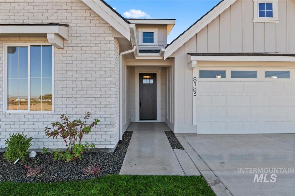 Entrance to property with board and batten siding, brick siding, and a garage