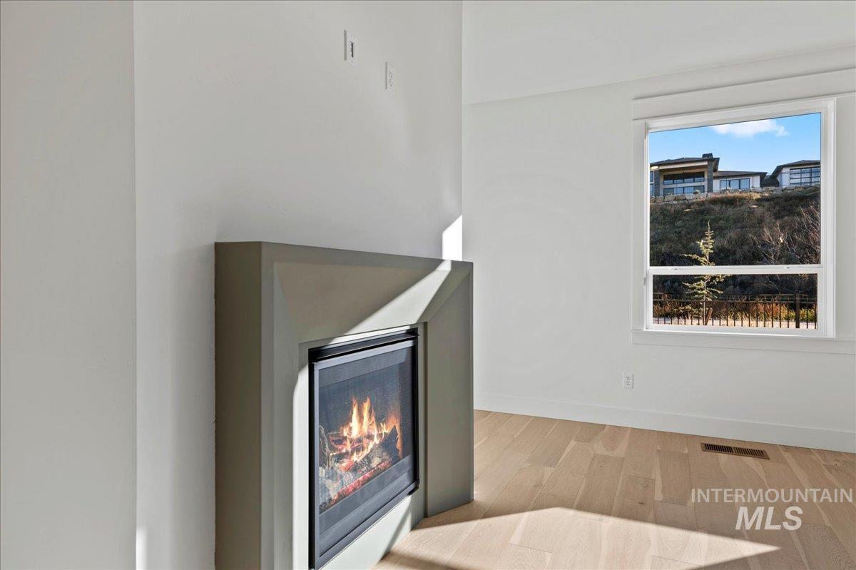 Detailed view of wood finished floors and a lit fireplace