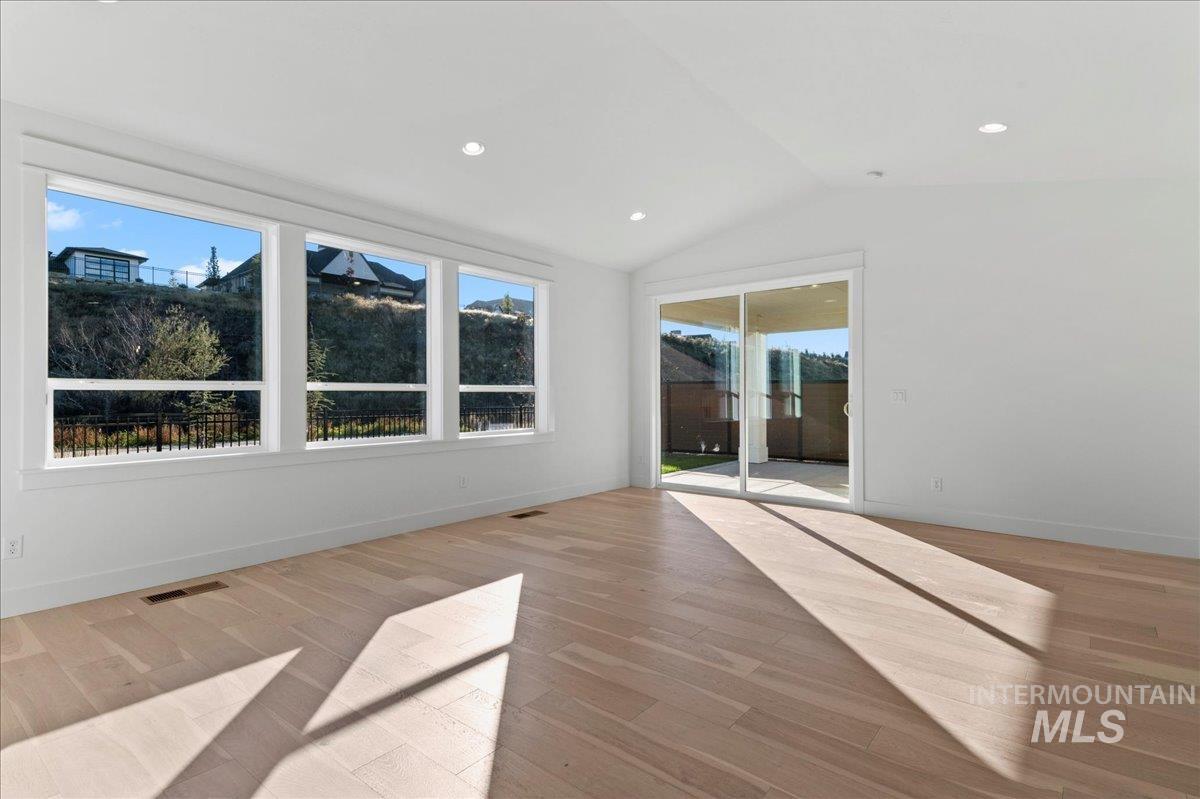 Empty room with lofted ceiling, light wood finished floors, and recessed lighting