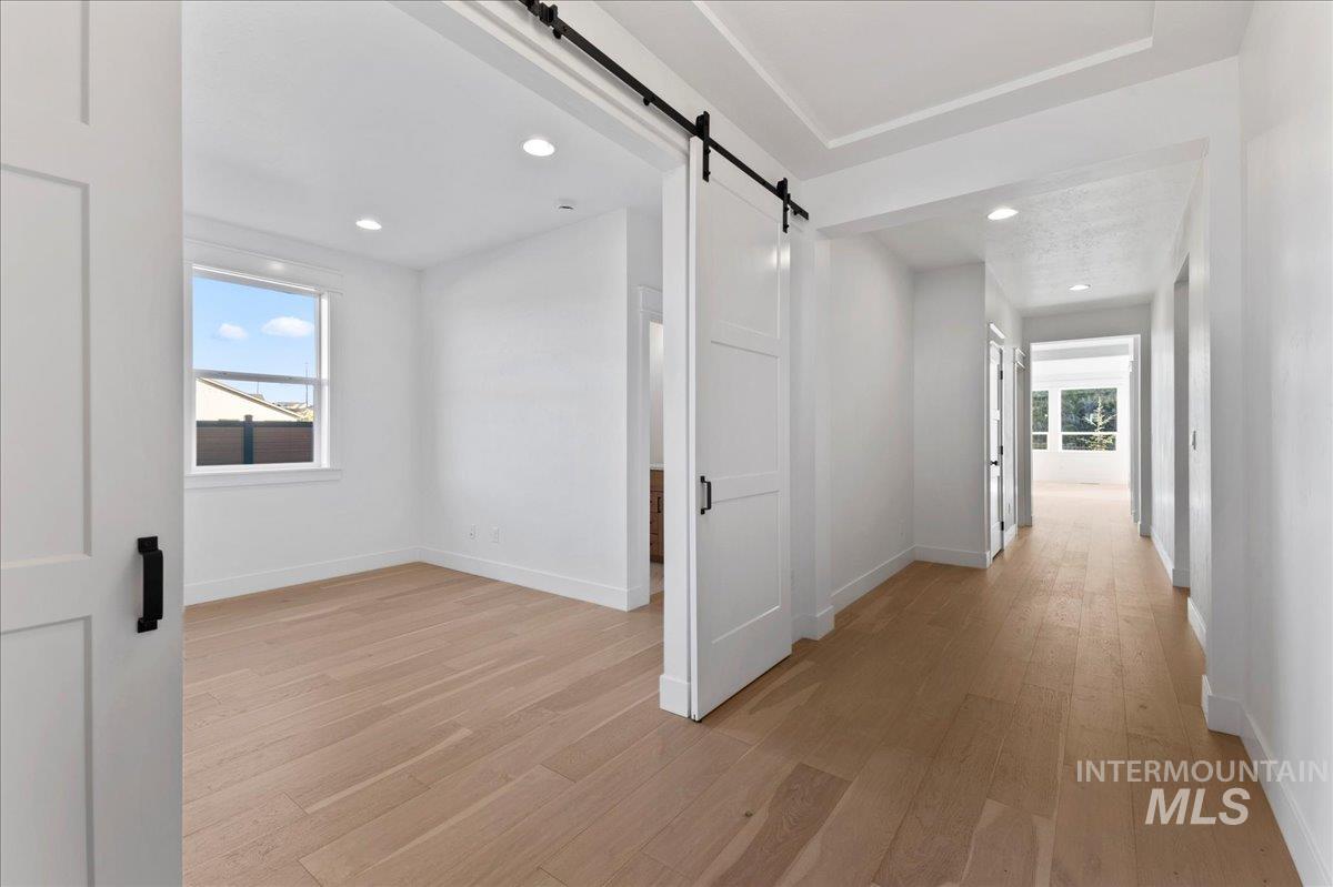 Corridor featuring a barn door, light wood-style flooring, and recessed lighting