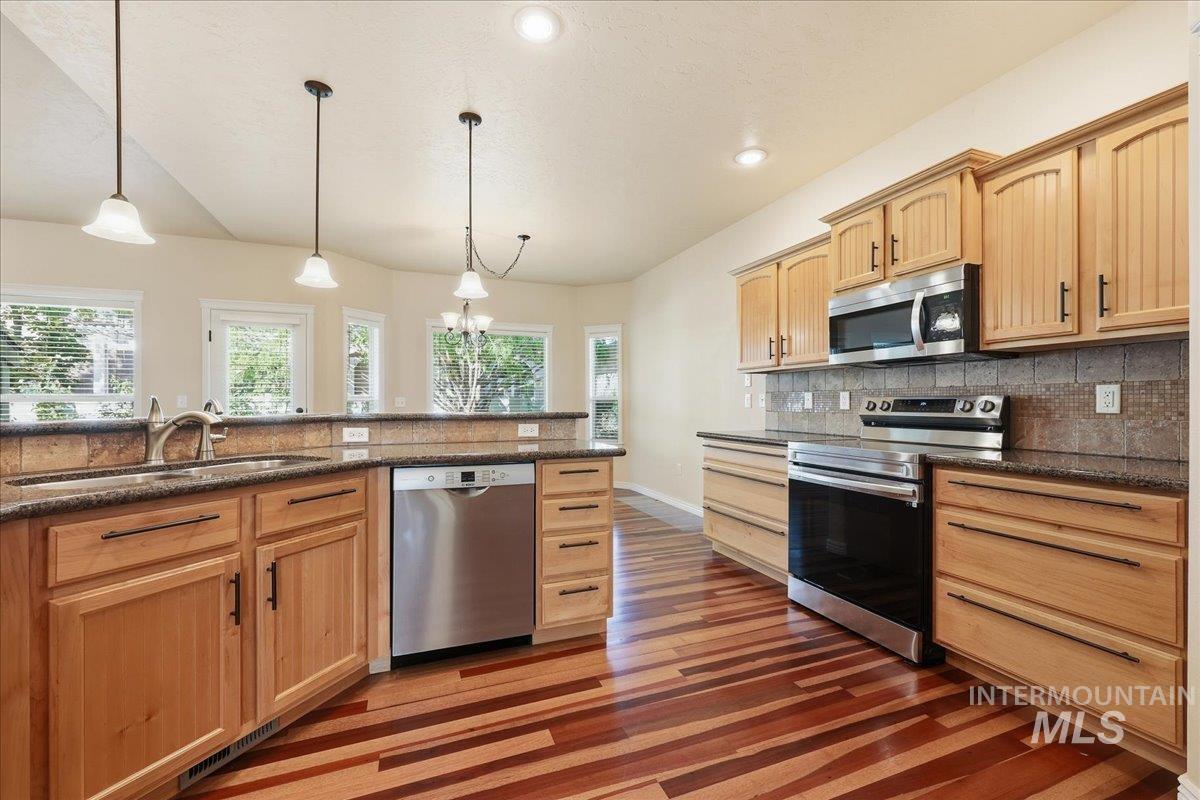 Kitchen with stainless steel appliances, light brown cabinetry, pendant lighting, healthy amount of natural light, and recessed lighting