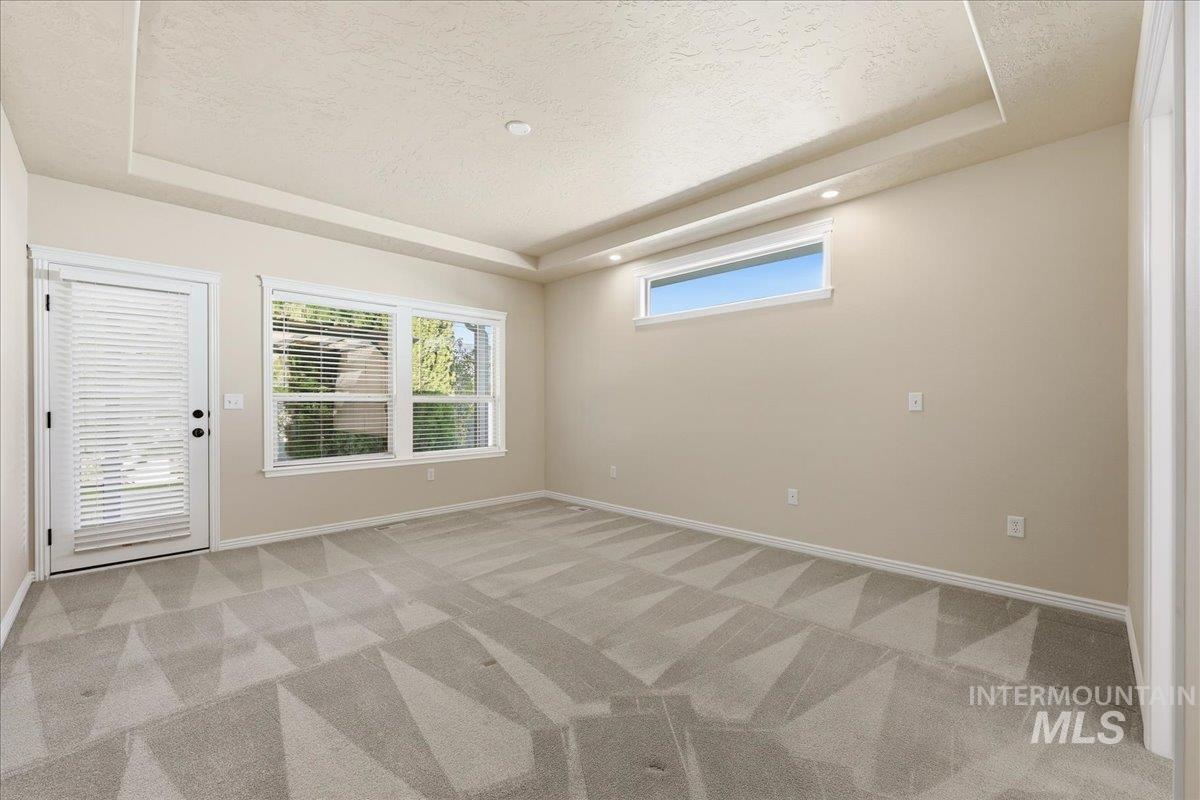 Spare room with a tray ceiling, light carpet, and a textured ceiling