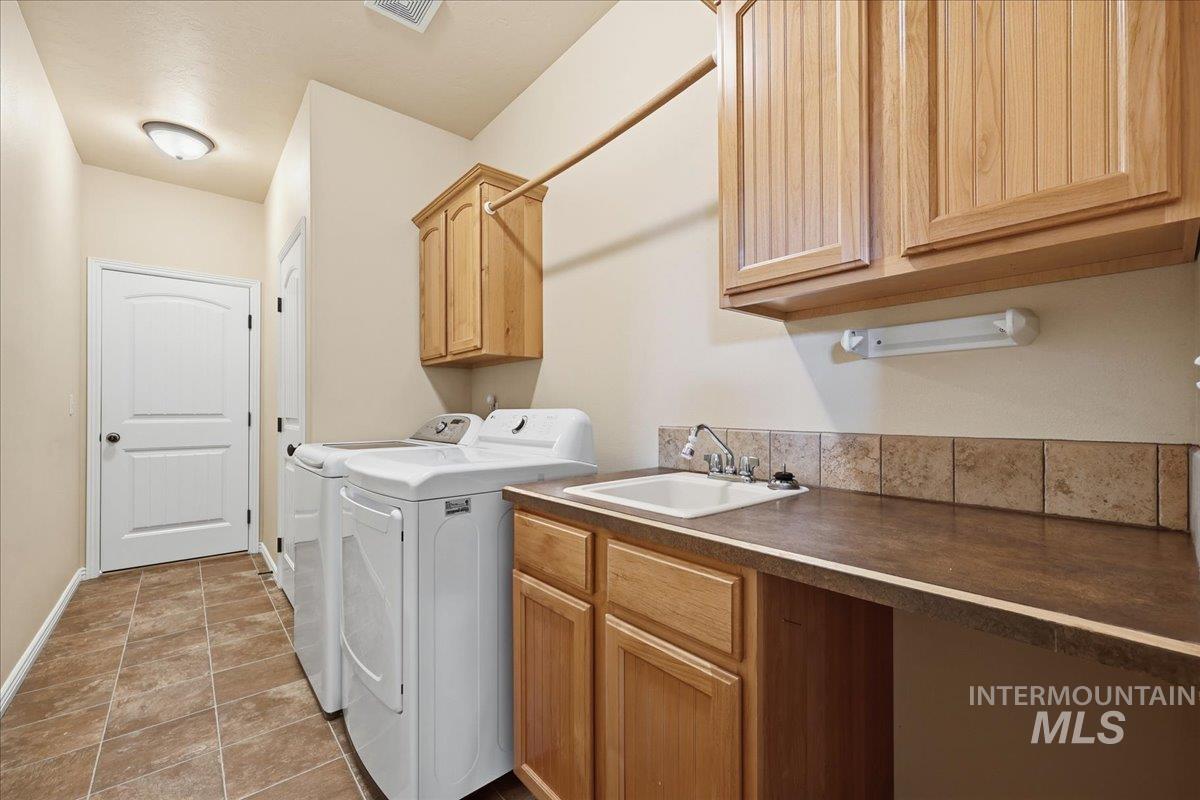 Laundry room featuring washing machine and clothes dryer, cabinet space, and light tile patterned flooring