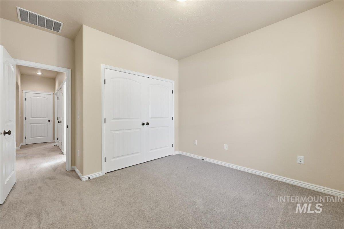 Unfurnished bedroom with light colored carpet and a closet