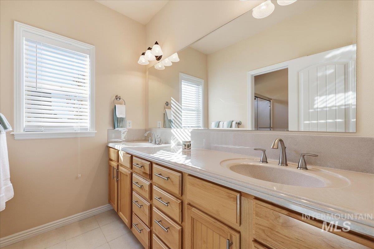 Full bath with double vanity and light tile patterned floors