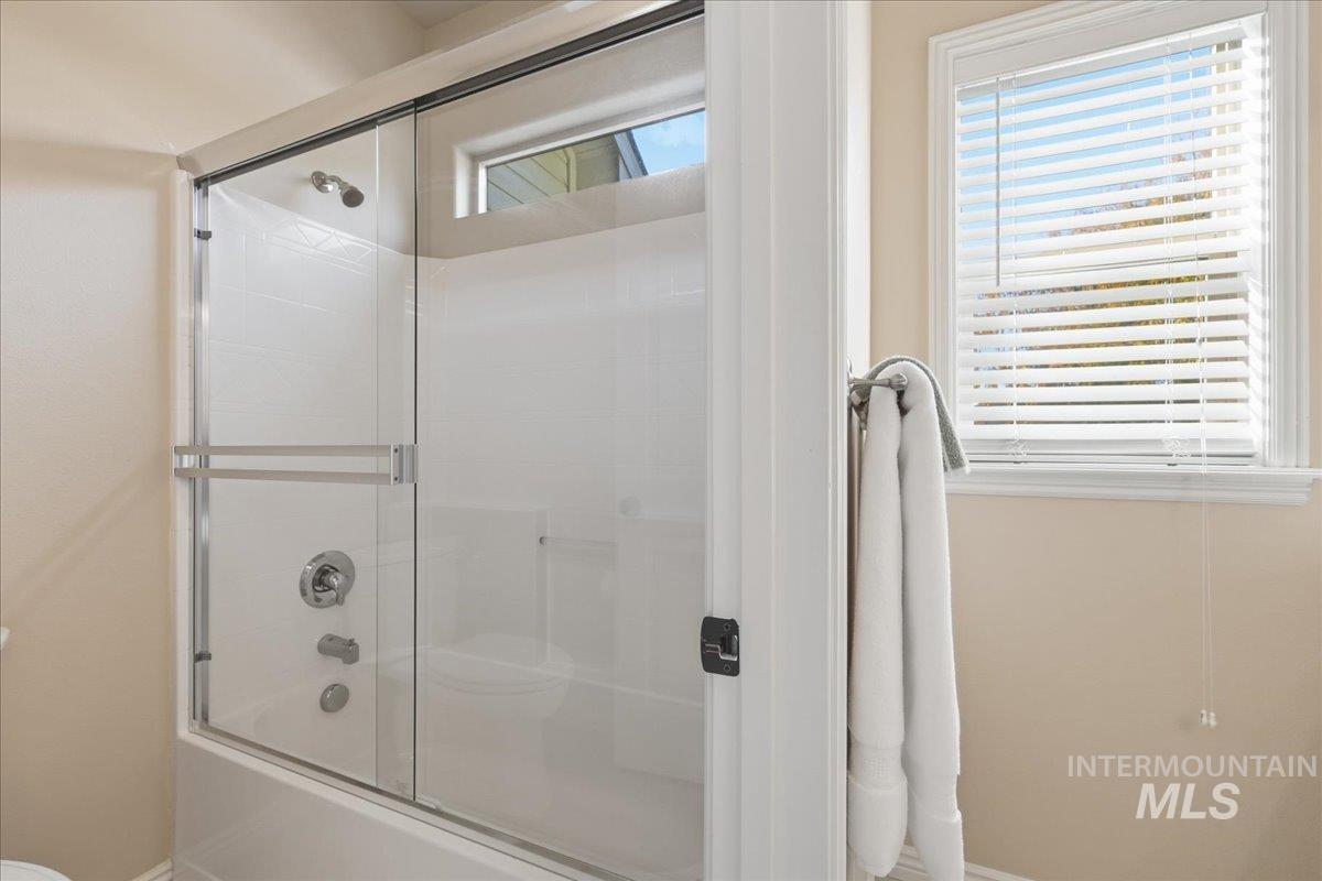 Bathroom with bath / shower combo with glass door and baseboards