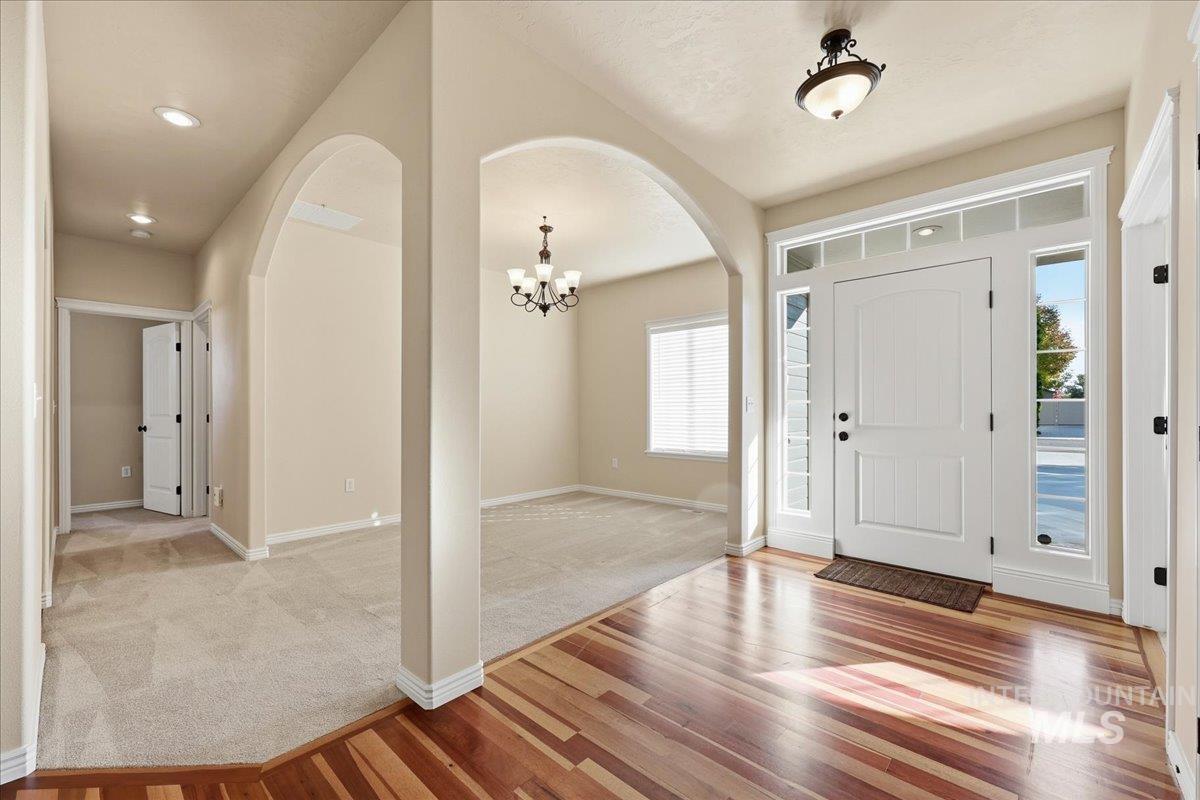 Entryway with a chandelier, light wood finished floors, light carpet, arched walkways, and recessed lighting