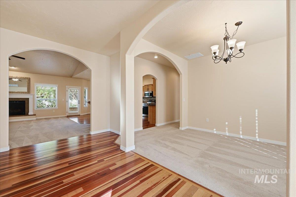 Unfurnished dining area with a fireplace with raised hearth, light wood-style floors, light colored carpet, and a chandelier