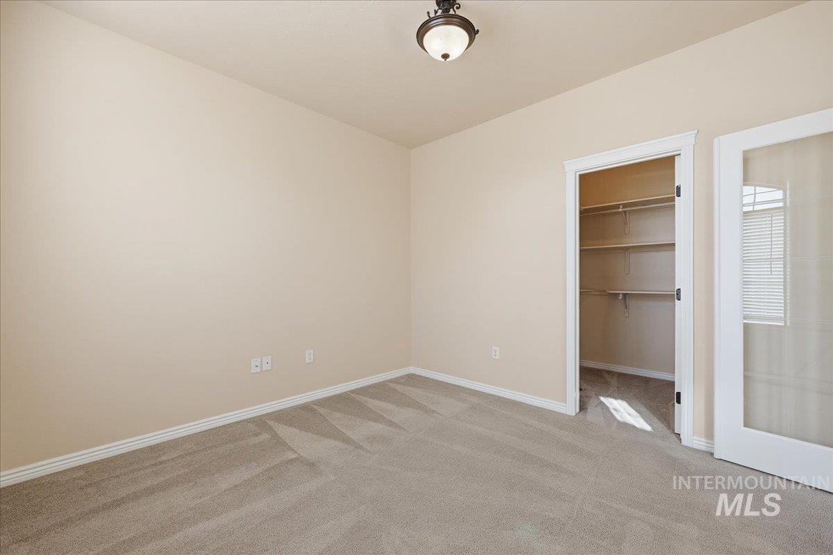 Unfurnished bedroom with light colored carpet and a walk in closet