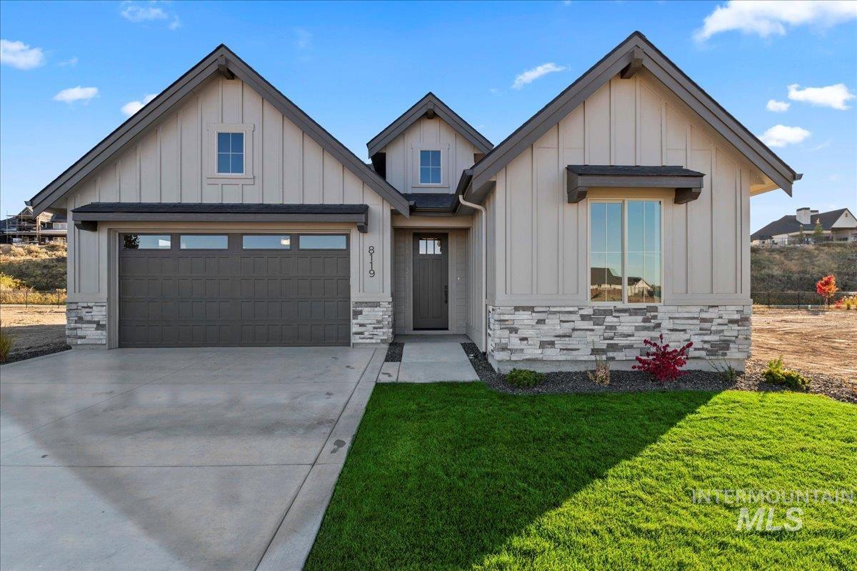 Modern inspired farmhouse featuring board and batten siding, stone siding, concrete driveway, and a garage