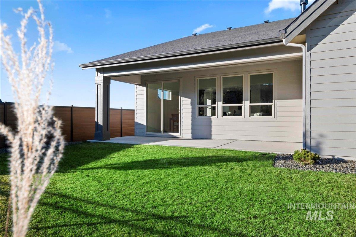Back of house featuring a patio and roof with shingles