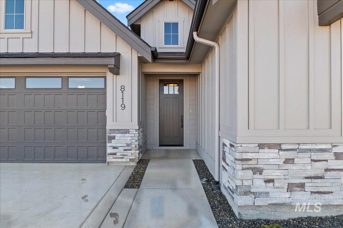 Doorway to property featuring stone siding, board and batten siding, and a garage