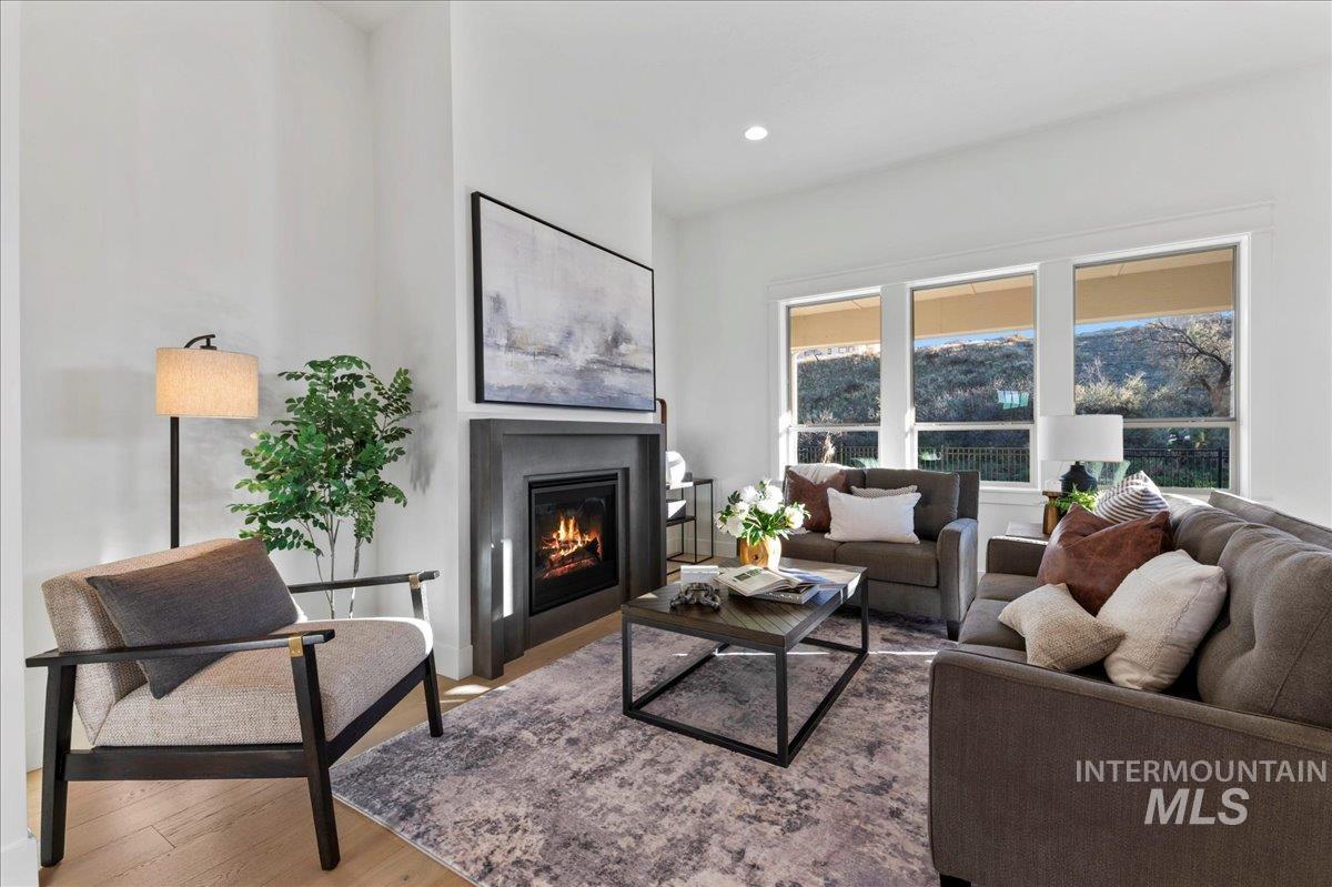 Living area with wood finished floors, a glass covered fireplace, and recessed lighting