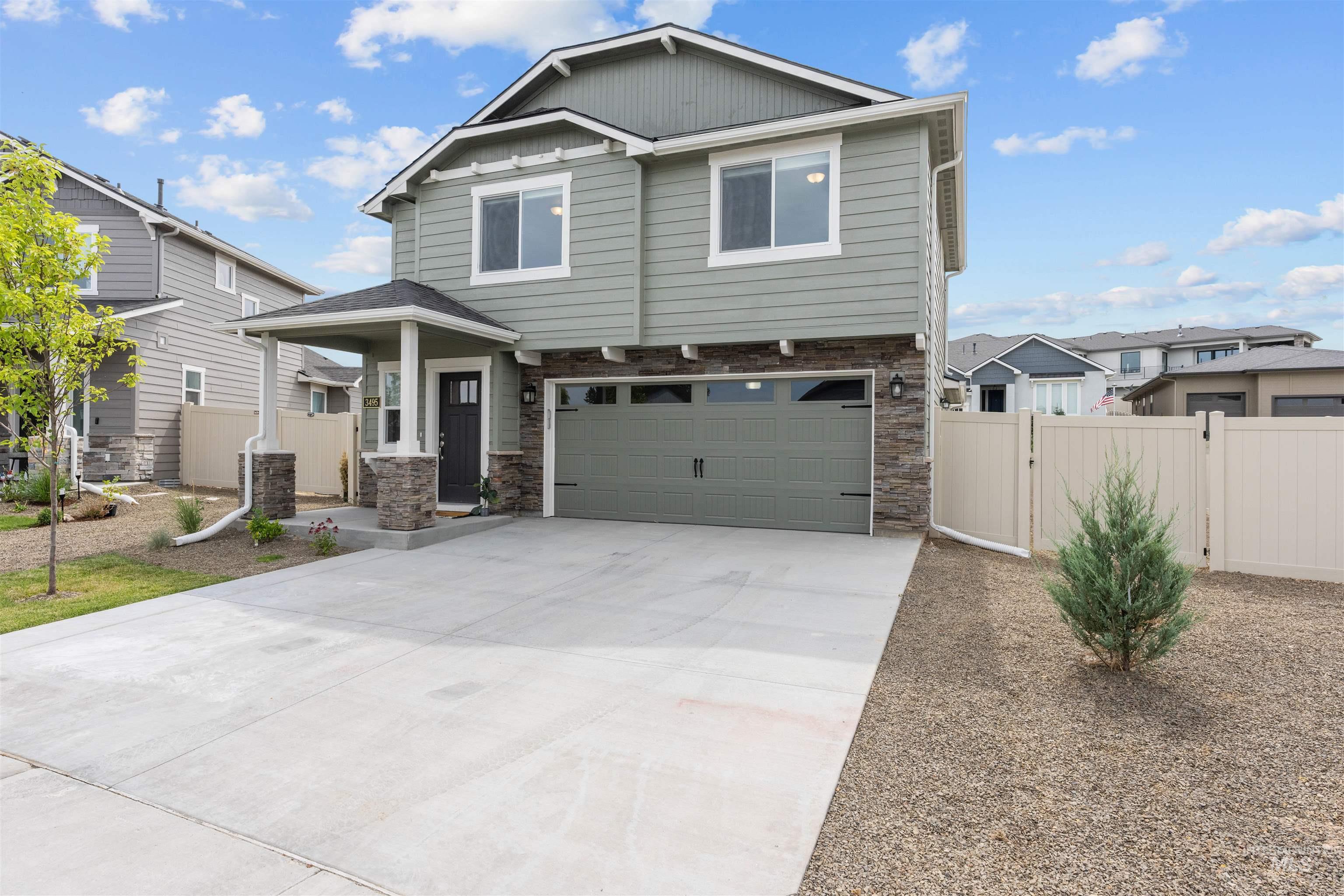 Craftsman-style home with concrete driveway, an attached garage, stone siding, and a gate
