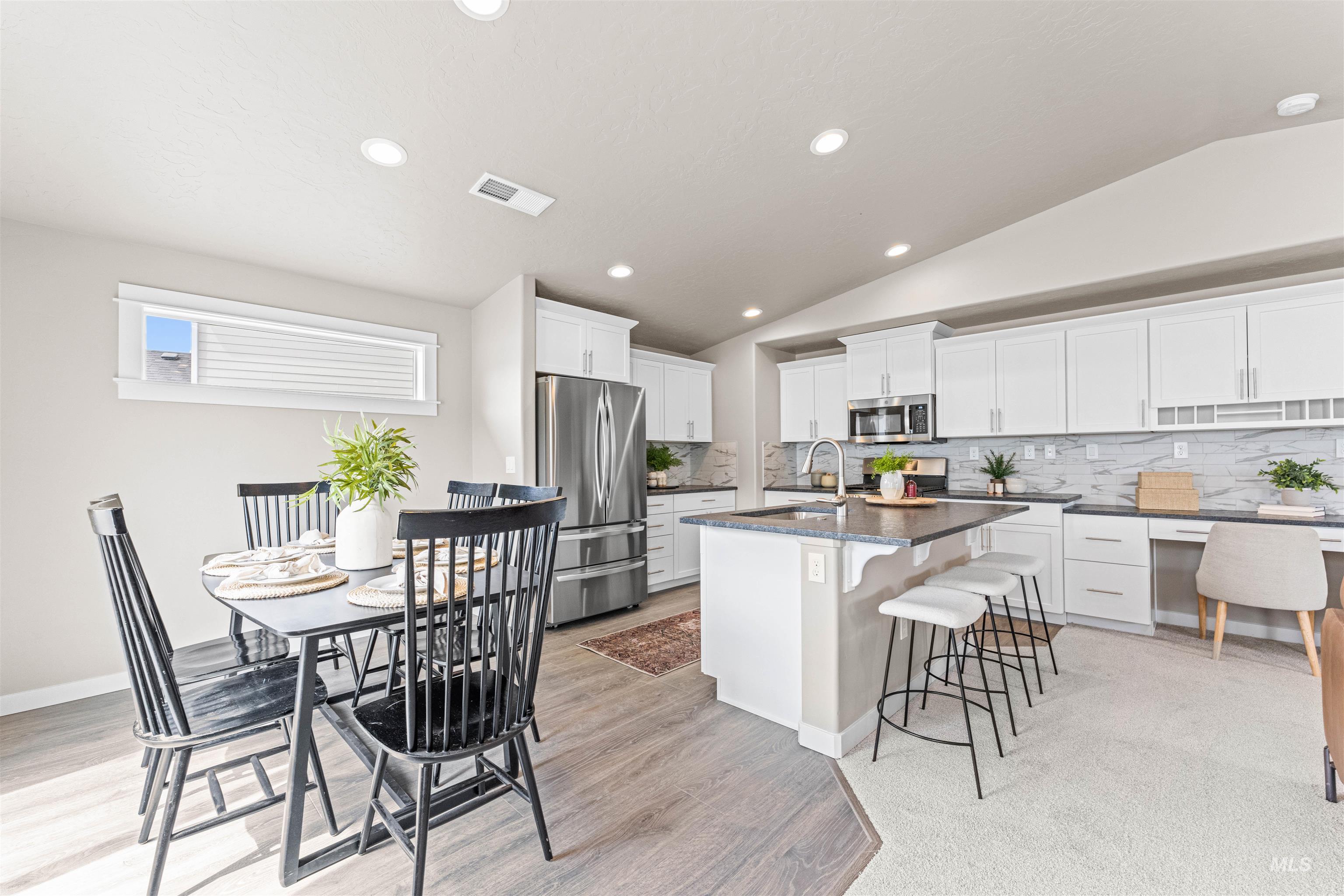 Kitchen with tasteful backsplash, recessed lighting, vaulted ceiling, a breakfast bar area, and white cabinets