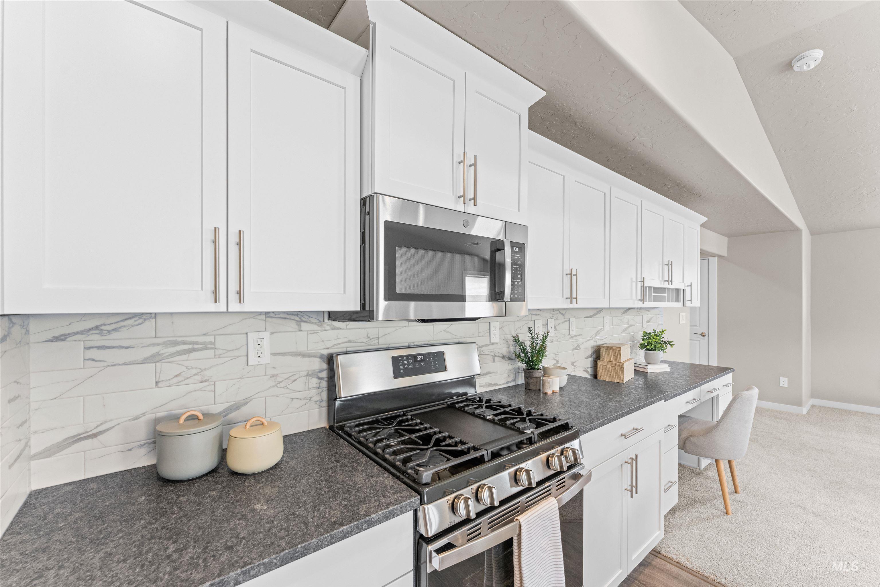 Kitchen featuring appliances with stainless steel finishes, decorative backsplash, white cabinets, dark stone counters, and a textured ceiling