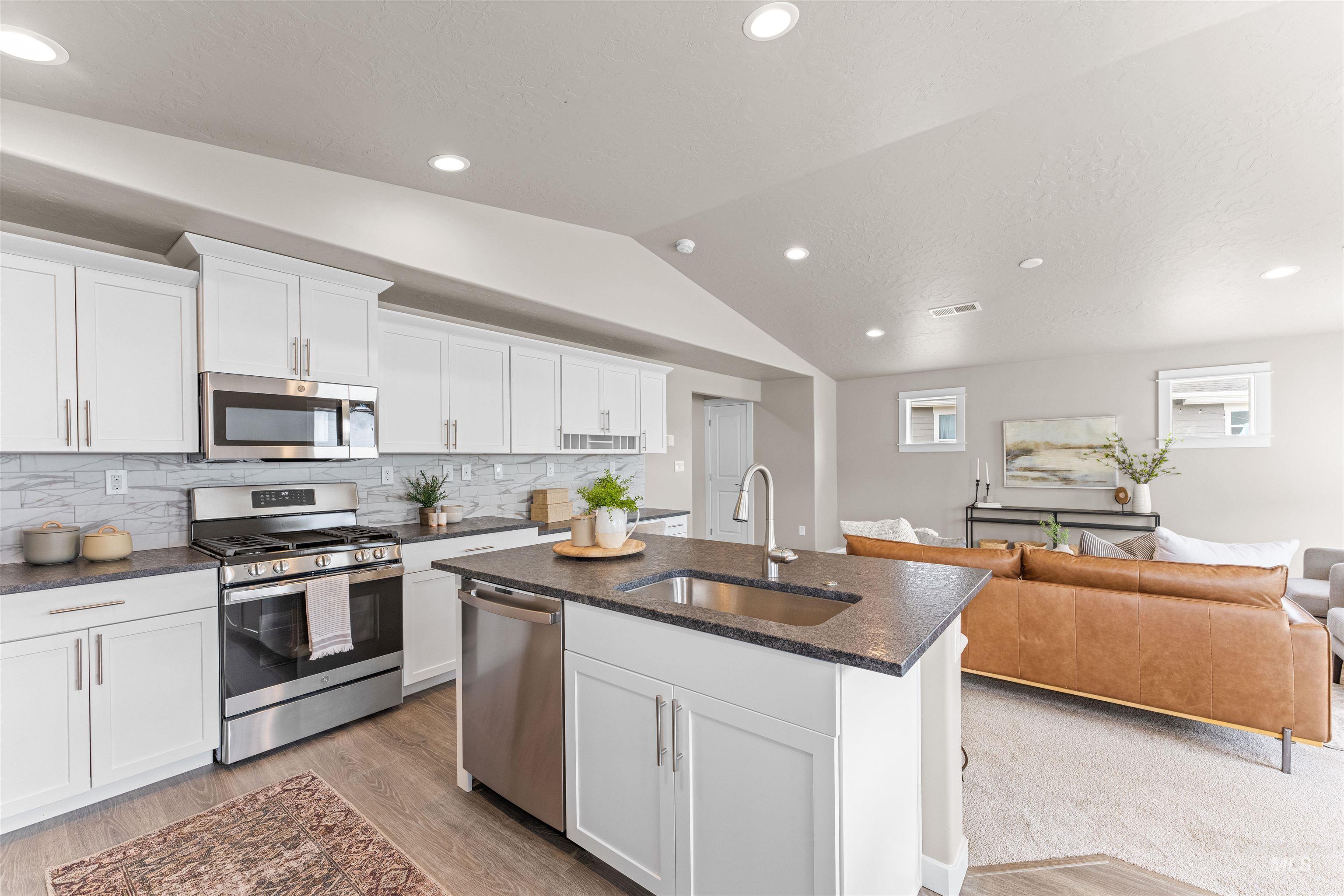 Kitchen with stainless steel appliances, white cabinets, open floor plan, recessed lighting, and decorative backsplash