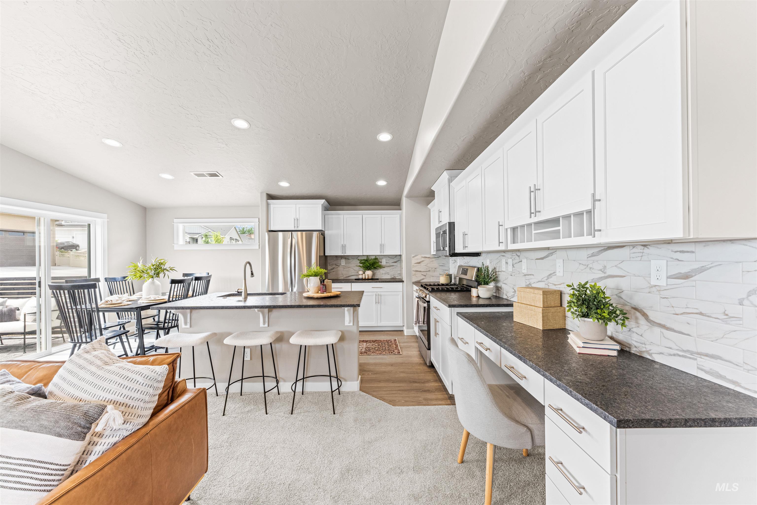 Kitchen featuring a breakfast bar, recessed lighting, decorative backsplash, stainless steel appliances, and an island with sink