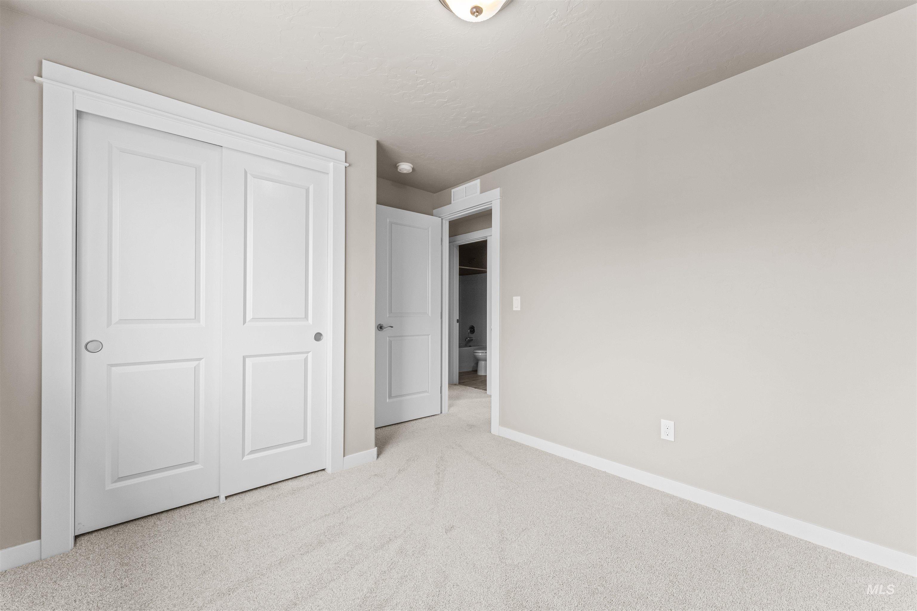 Unfurnished bedroom with light colored carpet and a closet