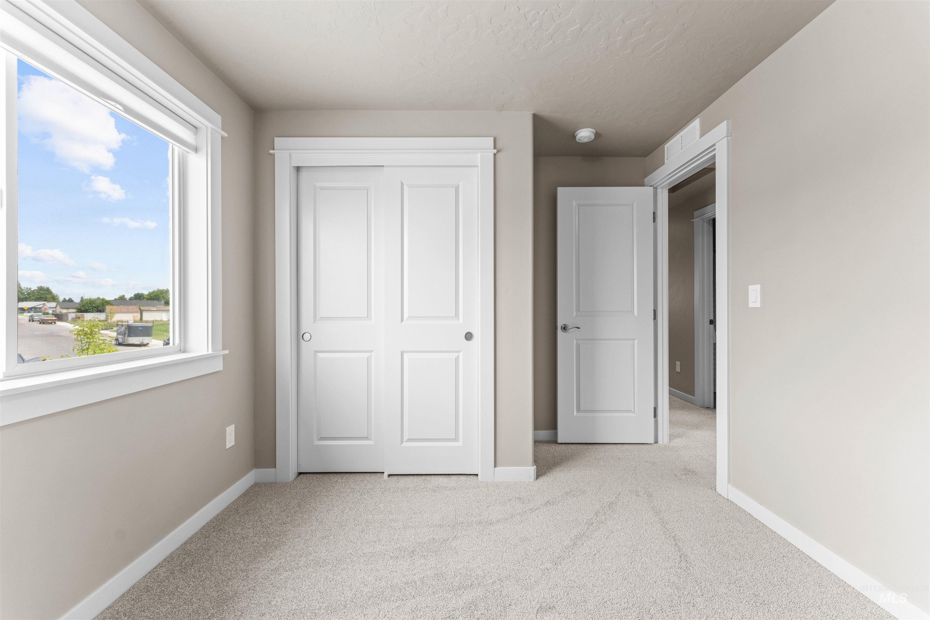 Unfurnished bedroom featuring light colored carpet, a closet, and a textured ceiling