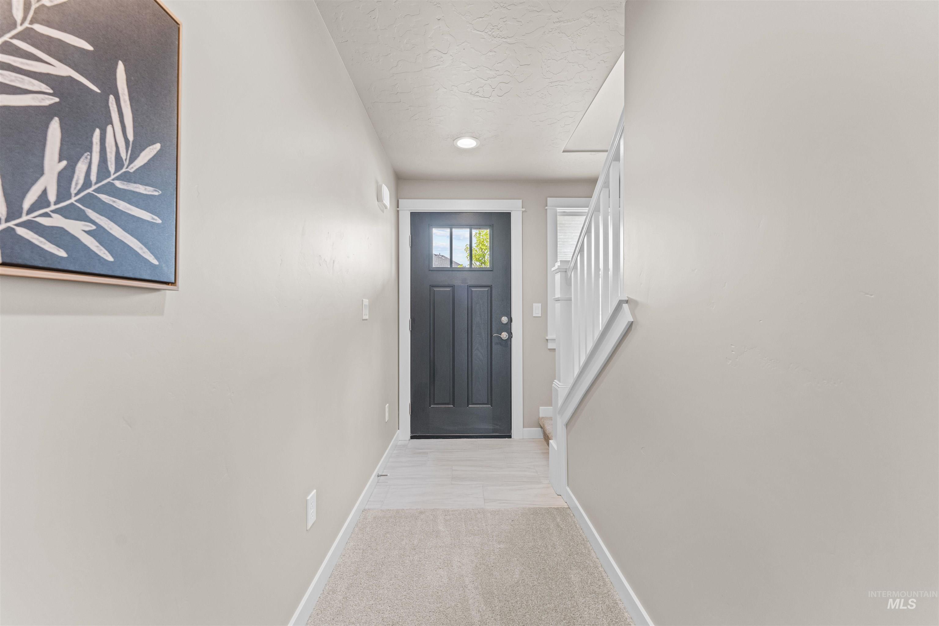 Entryway with carpet floors, stairs, and a textured ceiling