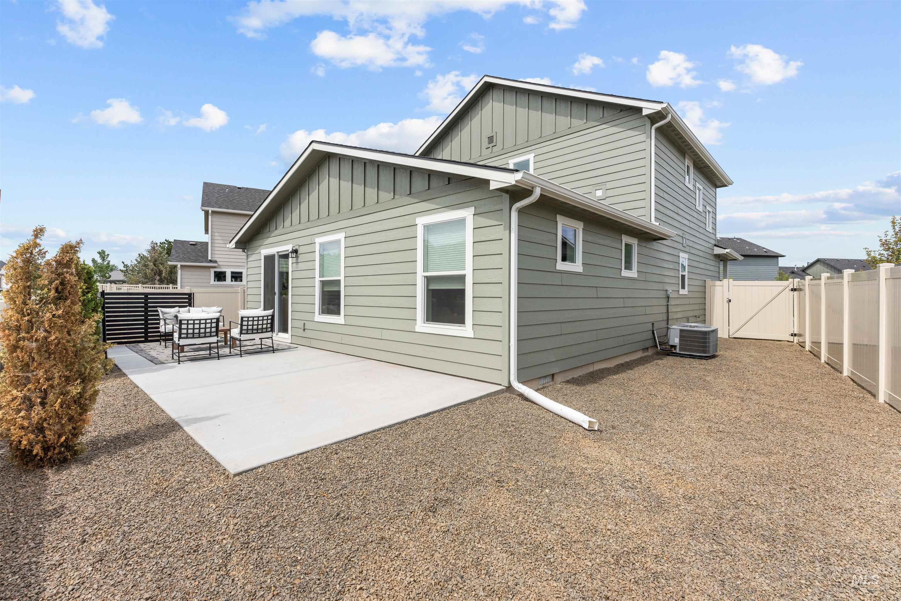 Back of property featuring board and batten siding, a patio, a fenced backyard, and a gate