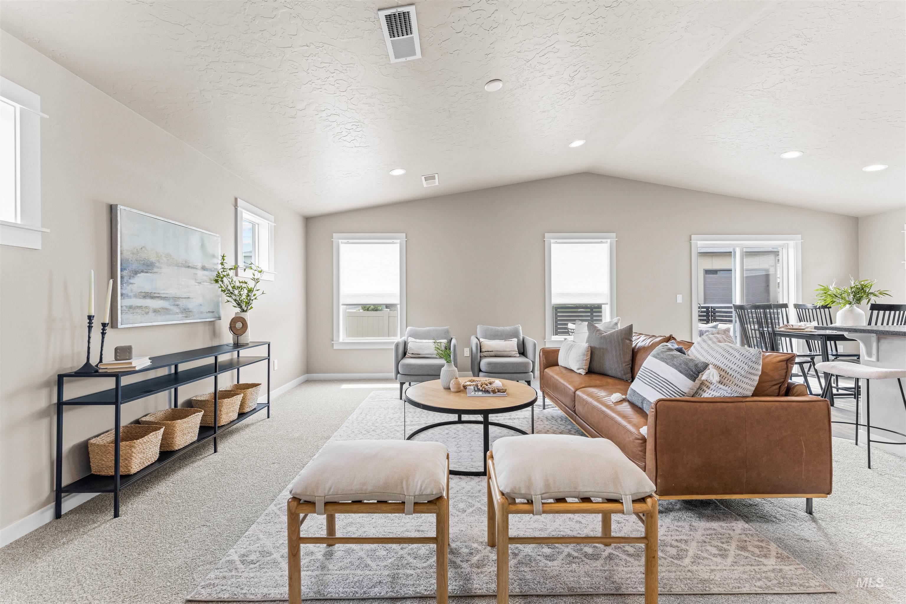 Living area with light carpet, healthy amount of natural light, lofted ceiling, a textured ceiling, and recessed lighting