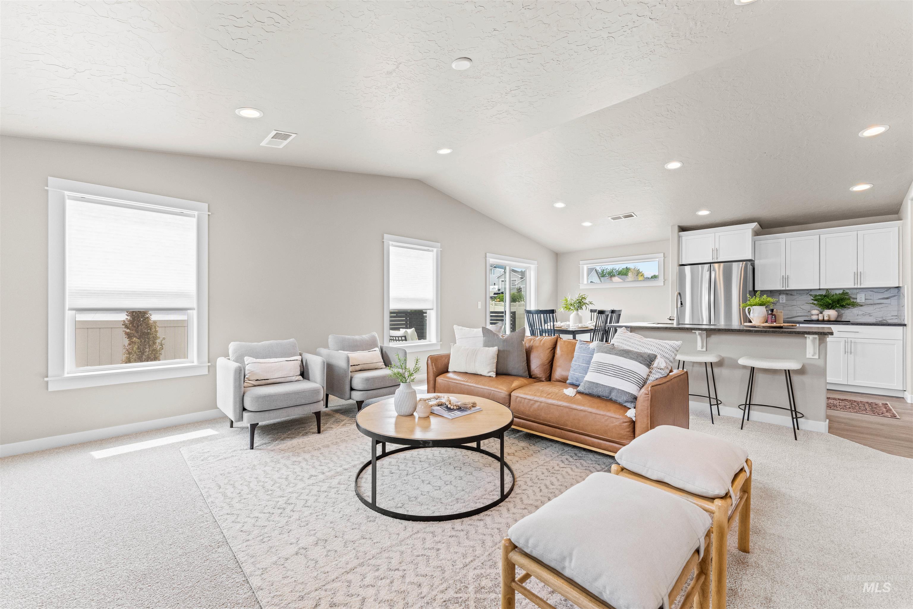 Living area with recessed lighting, light colored carpet, lofted ceiling, and a textured ceiling