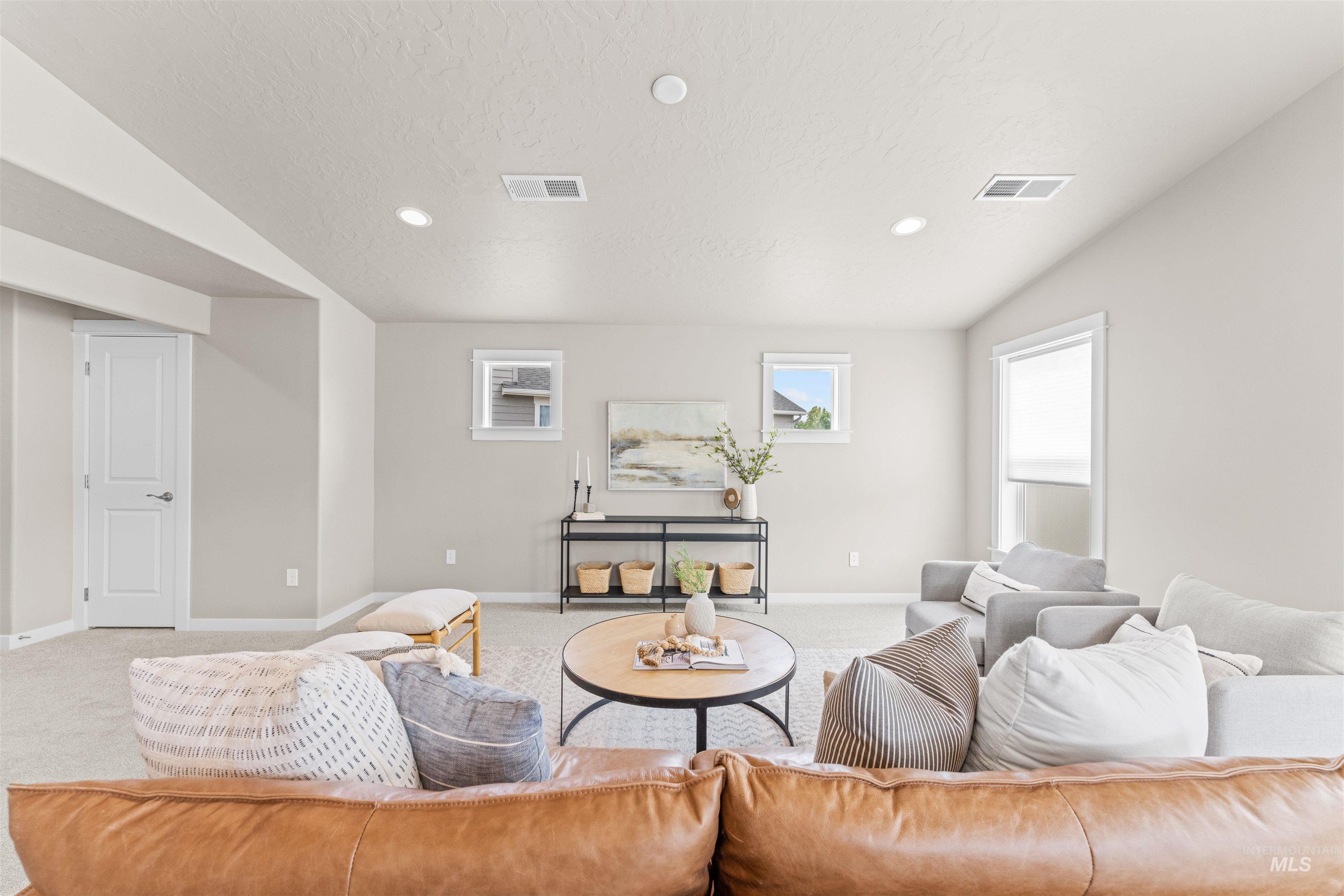 Carpeted living room with recessed lighting, vaulted ceiling, and a textured ceiling
