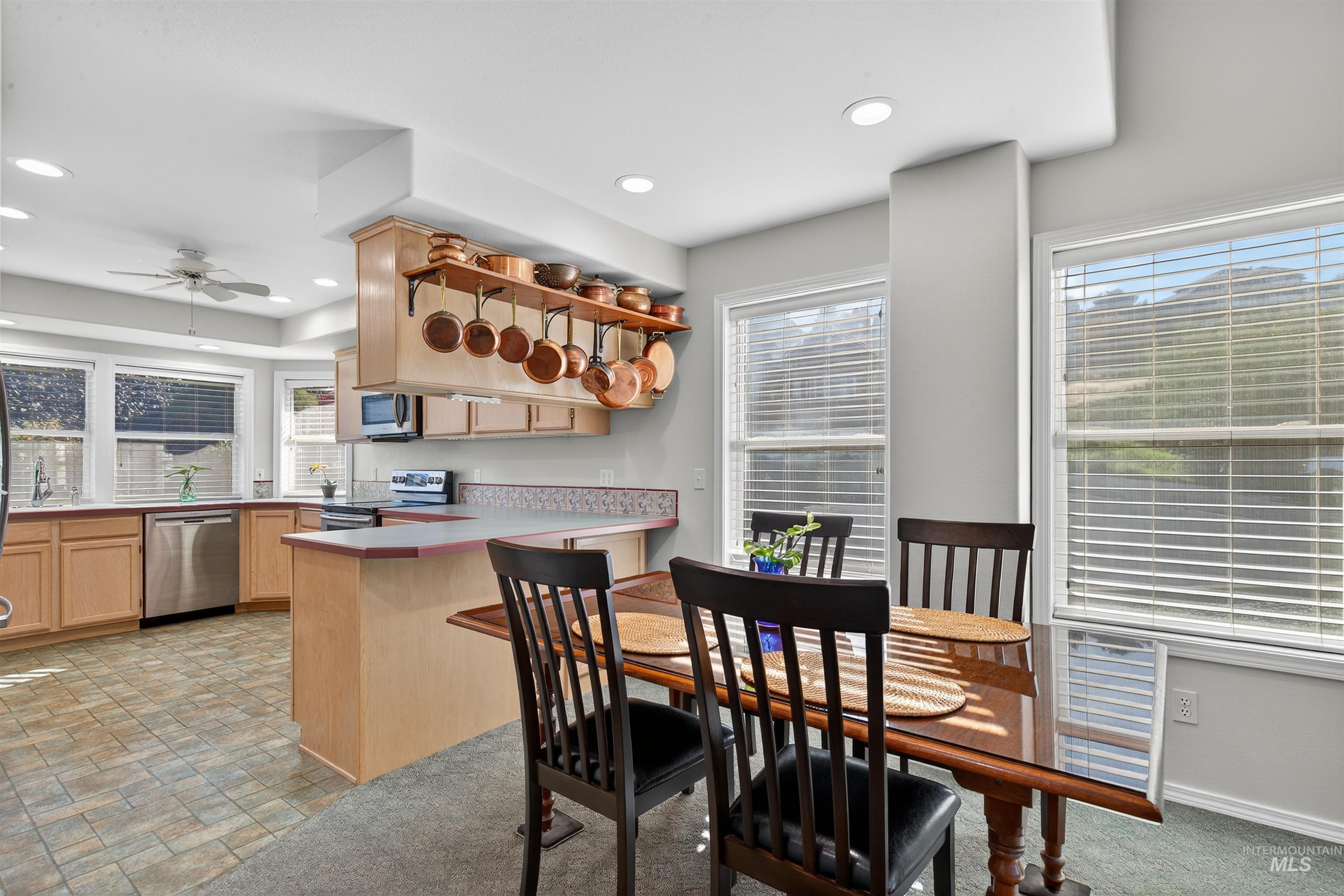 Kitchen featuring light brown cabinets, light countertops, a peninsula, appliances with stainless steel finishes, and open shelves