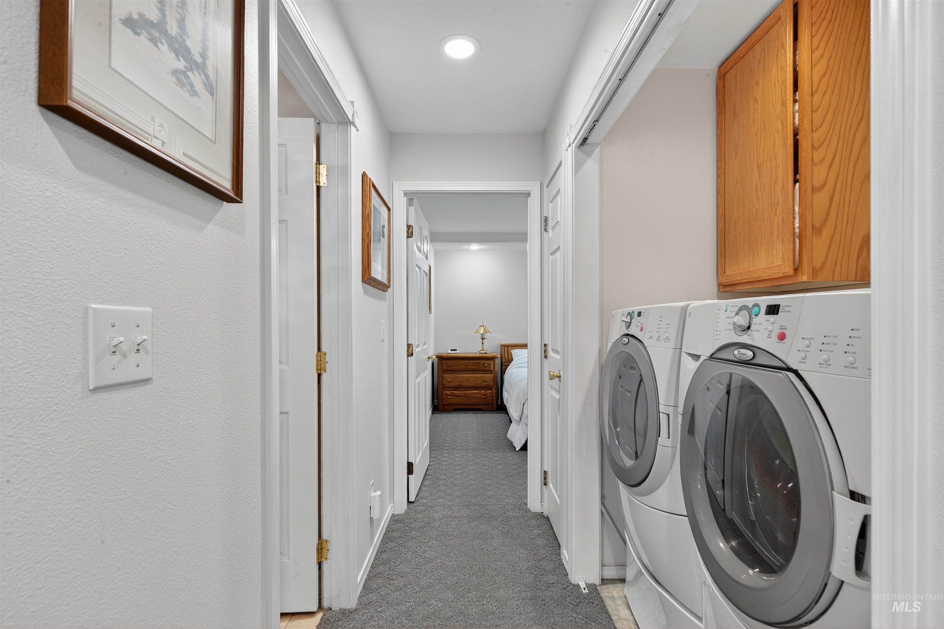 Washroom featuring light colored carpet, washing machine and dryer, and cabinet space
