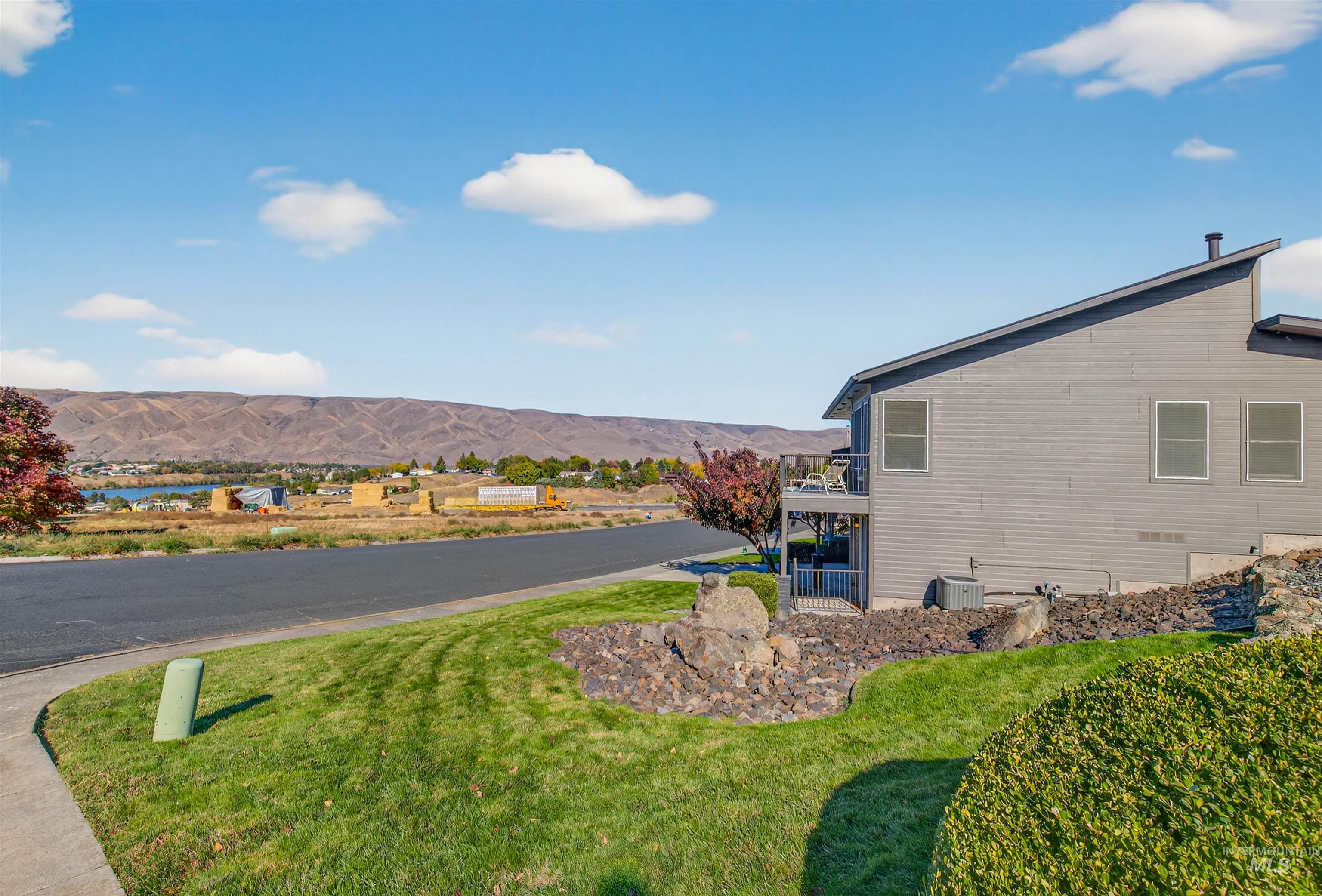 View of side of property with a mountain view, a balcony, and a lawn