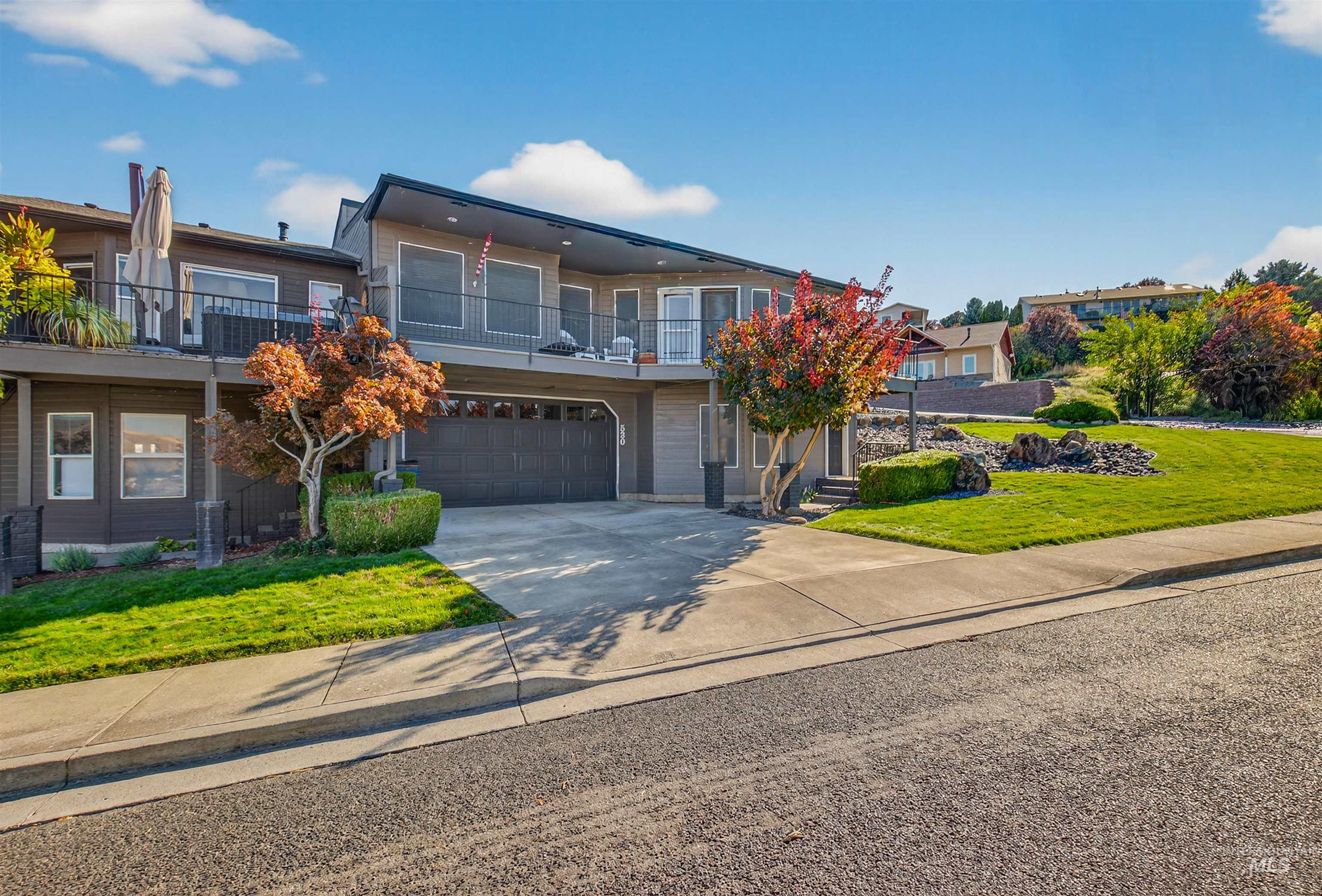View of front of property with a front yard, a balcony, concrete driveway, and a garage