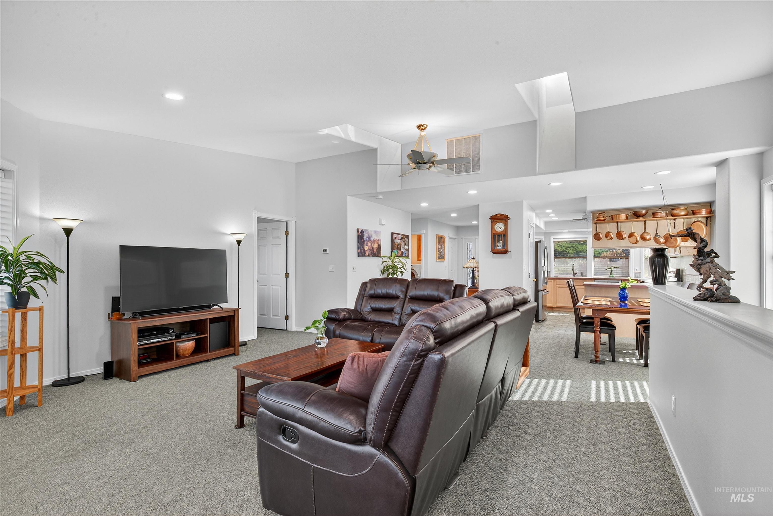 Living area with recessed lighting, light carpet, and a ceiling fan