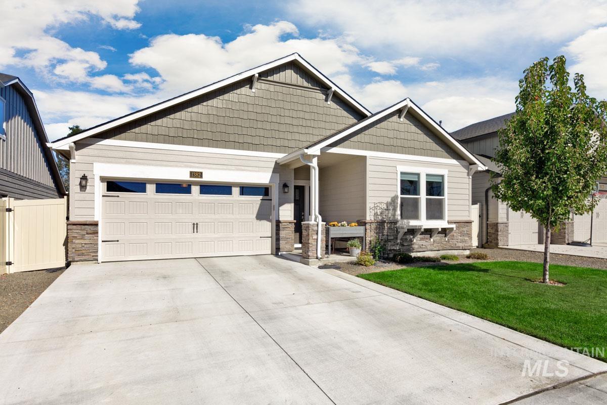 Craftsman inspired home with stone siding, a garage, concrete driveway, and a front lawn