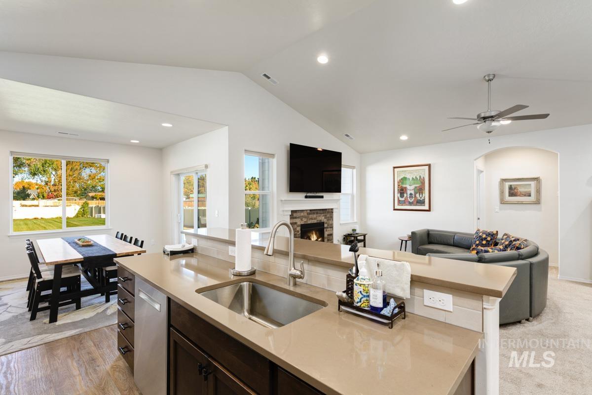 Kitchen with open floor plan, dark brown cabinets, vaulted ceiling, recessed lighting, and an island with sink