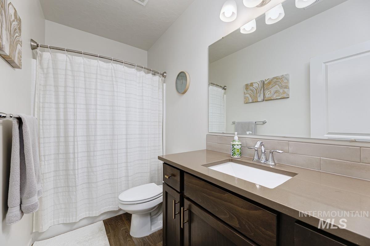 Bathroom with a shower with curtain, vanity, and dark wood-type flooring