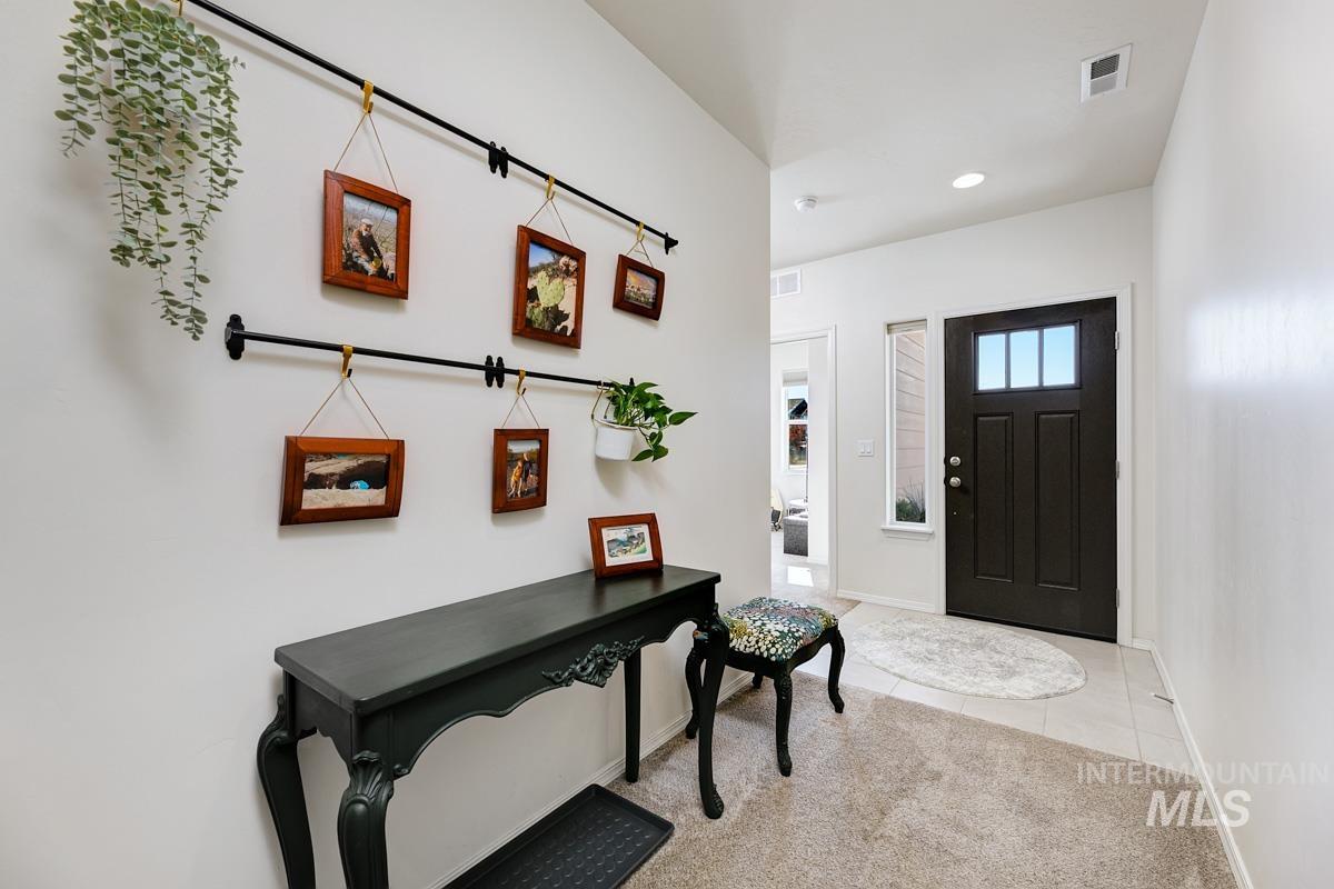 Foyer with light tile patterned floors, light carpet, and recessed lighting