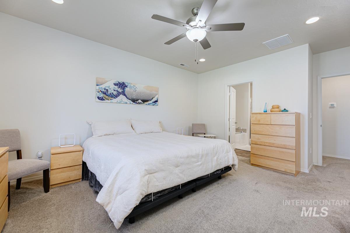 Bedroom featuring recessed lighting, light carpet, ceiling fan, and ensuite bath